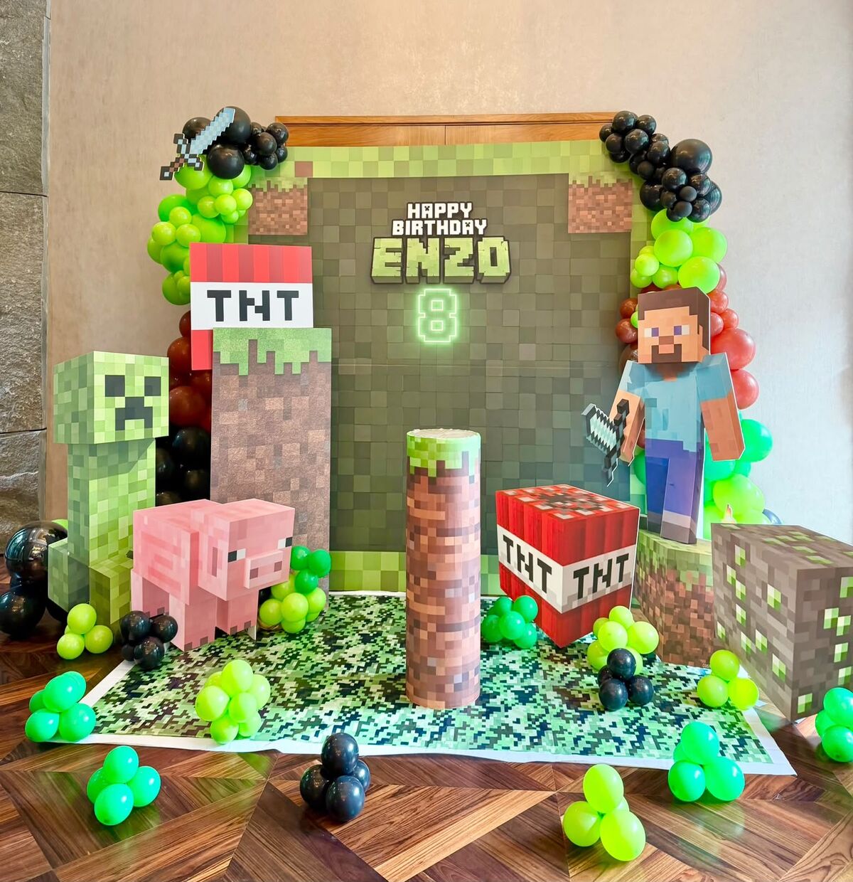 A Minecraft-themed birthday backdrop with balloon garlands, TNT and character cut-outs — styled by LinkNow Events Co. for Enzo's 8th birthday
